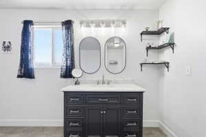 Bathroom vanity featuring a dark finish, integrated sink, and stone-finish countertop