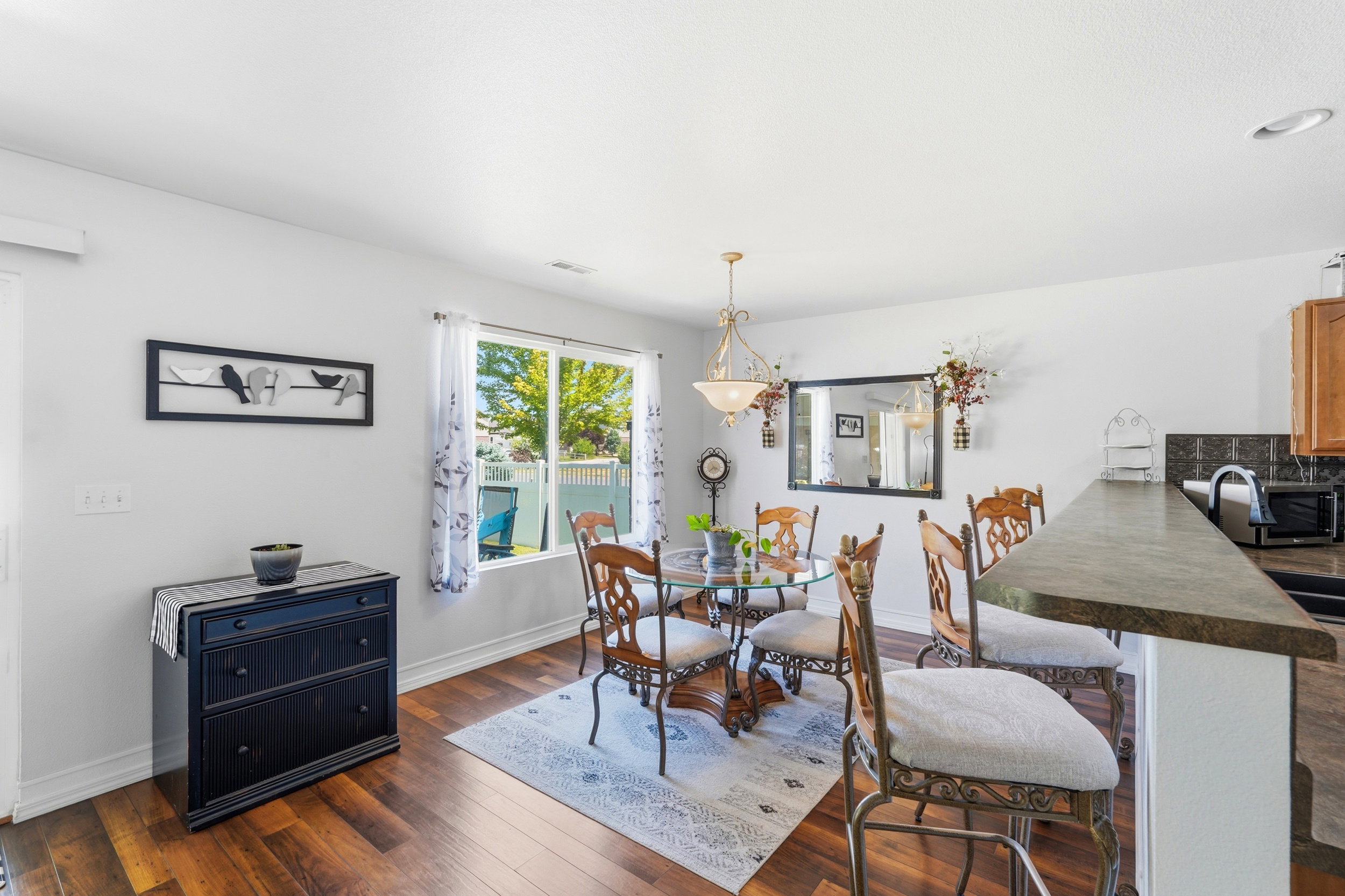 Dining area with wood-finish flooring, a large window, and a built-in breakfast bar with stone-look countertop