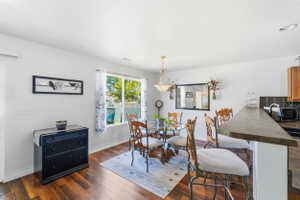 Dining area with wood-finish flooring, a large window, and a built-in breakfast bar with stone-look countertop