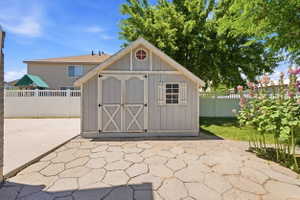 Gable-roof storage shed featuring board and batten siding with decorative double doors
