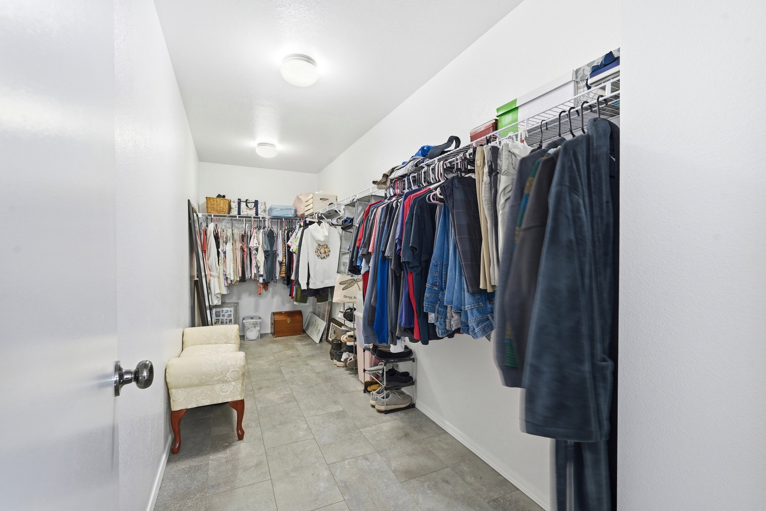 Spacious walk-in closet featuring light-toned tile flooring, built-in wire shelving, and recessed lighting fixtures