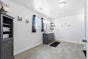 Spacious room featuring a dark grey vanity with dual sinks, overhead lighting, and built-in shelving