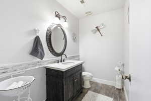 Bathroom featuring a dark wood vanity with a white countertop and oval sink, a decorative framed mirror, and a two-light vanity fixture