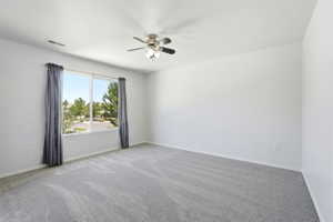 Bright room featuring a large window, plush gray carpeting, white walls, and a ceiling fan with integrated lighting