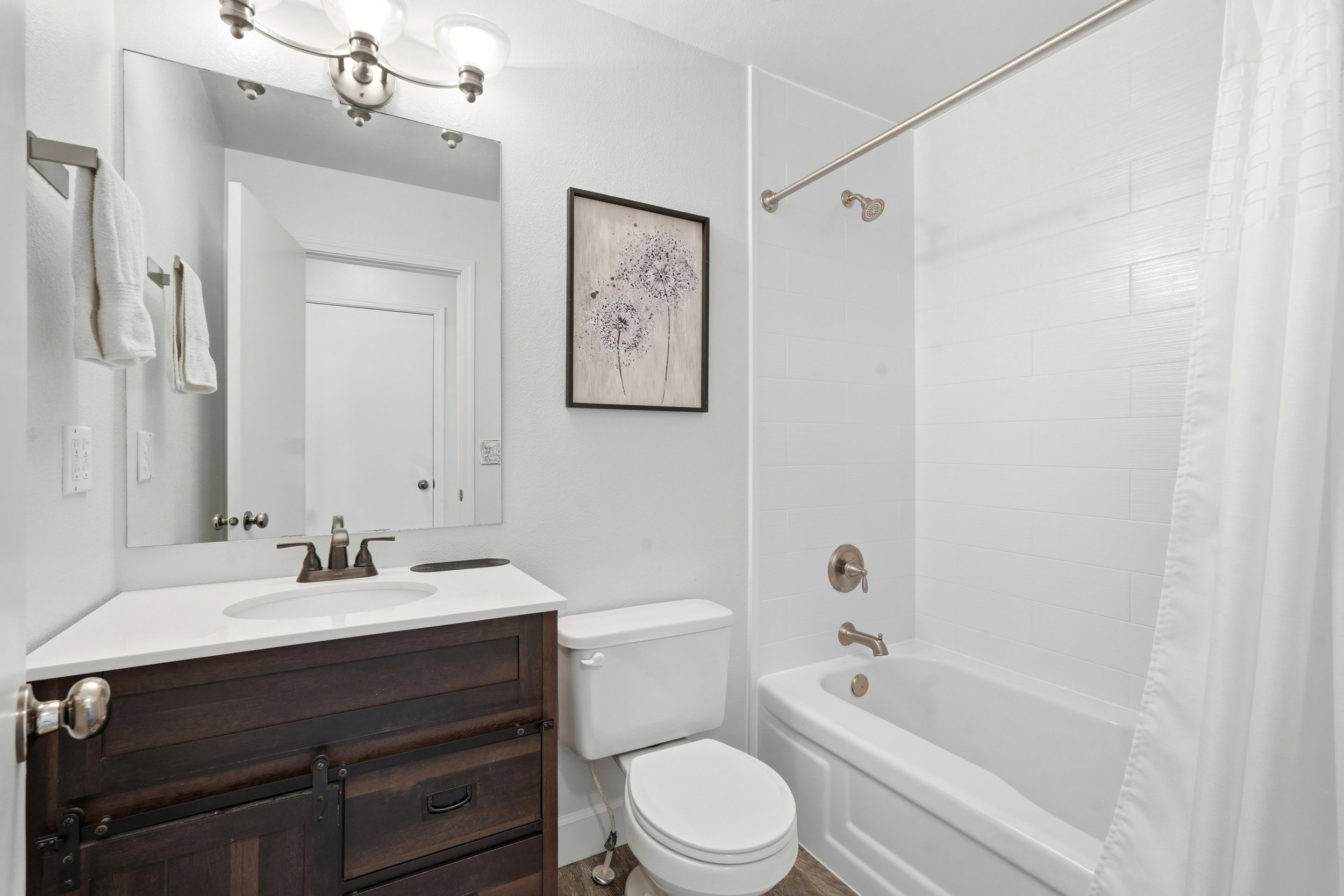Bathroom featuring a wood-finish vanity with a white countertop, an undermount sink, and a bronze-finish faucet
