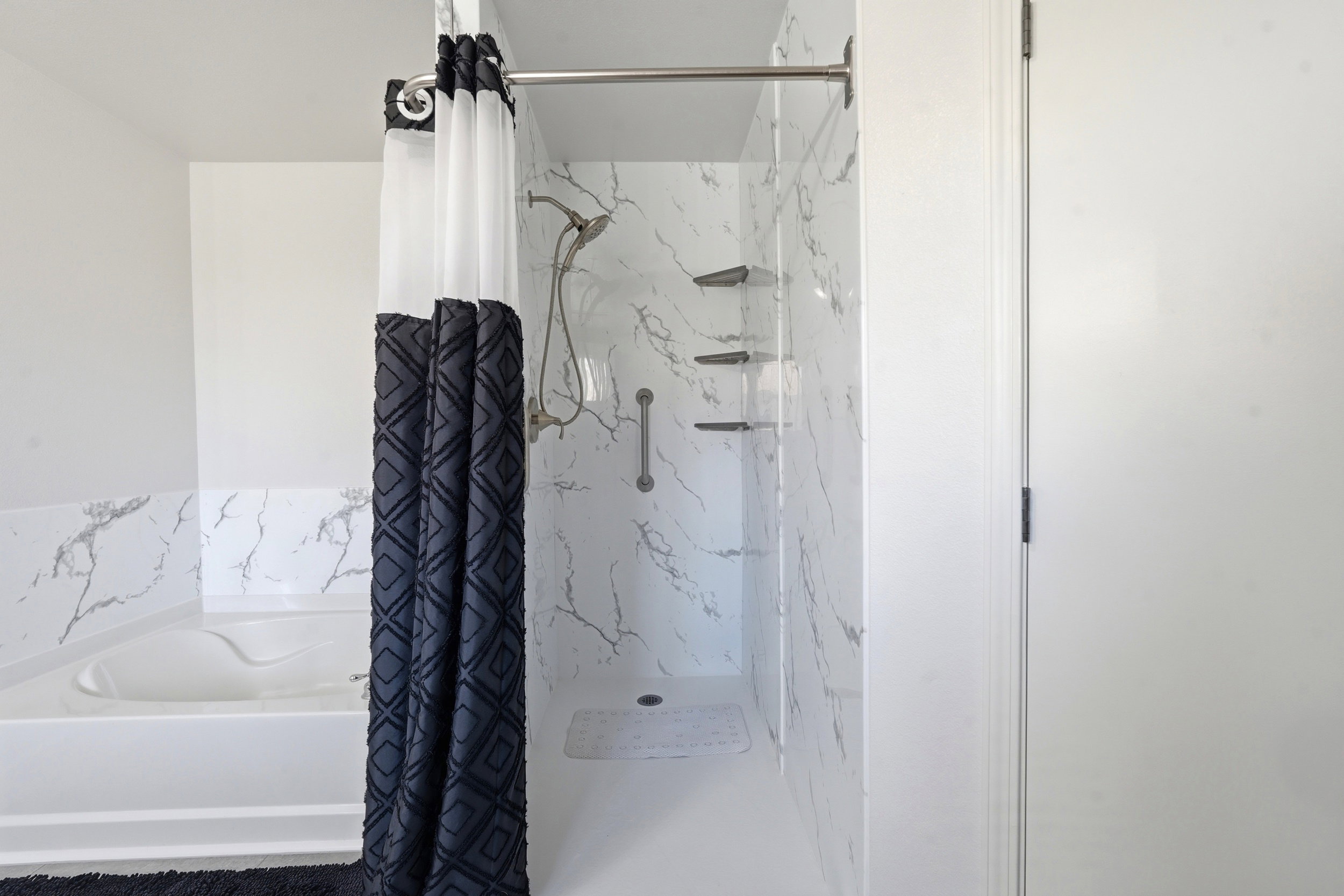 Walk-in shower with a multi-function showerhead, integrated shelving, and a grab bar