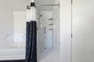 Walk-in shower with a multi-function showerhead, integrated shelving, and a grab bar