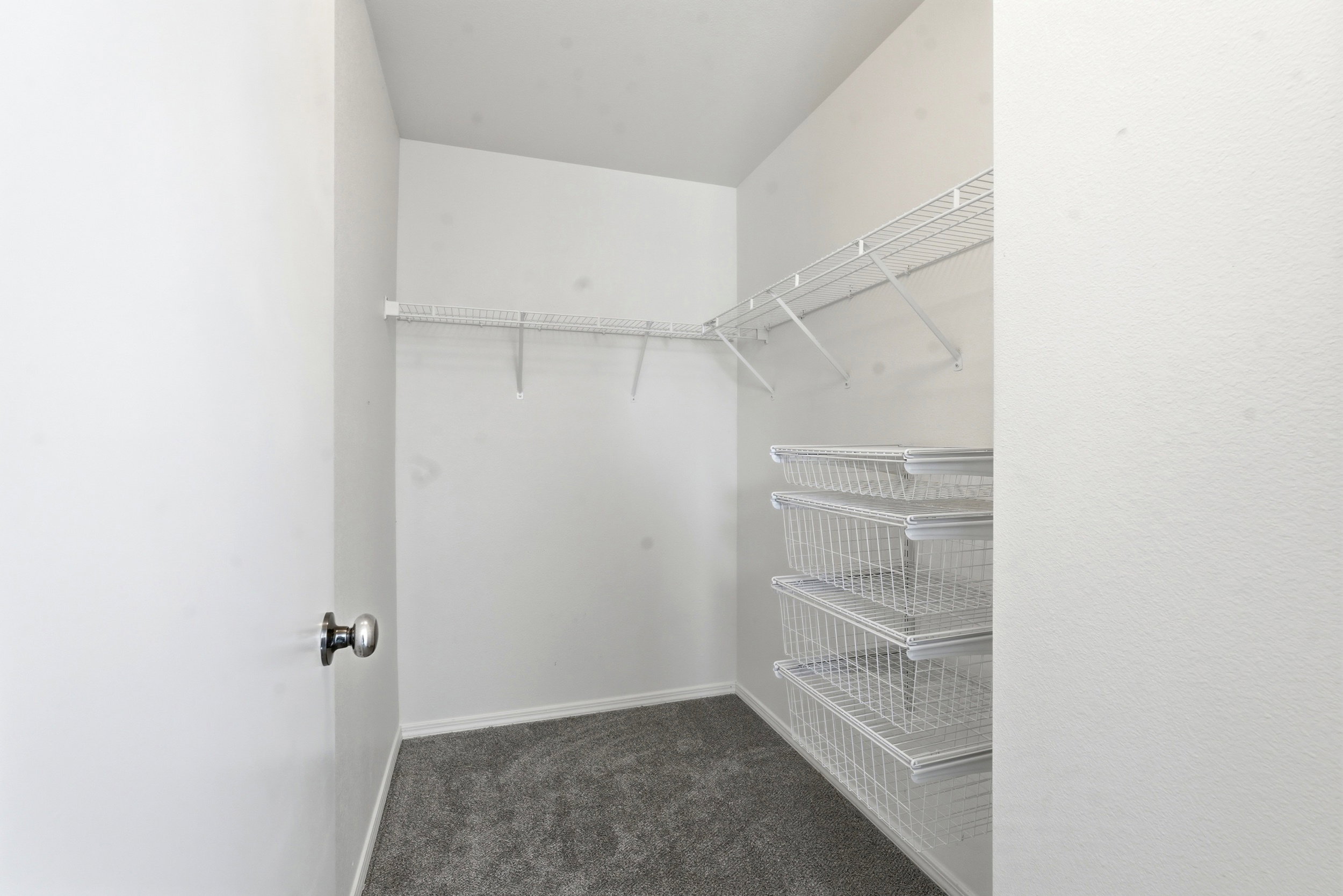 Walk-in closet featuring built-in wire shelving and integrated wire storage baskets