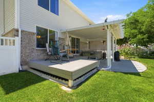 Expansive backyard featuring a covered patio with a hot tub, an elevated composite deck, and a manicured lawn