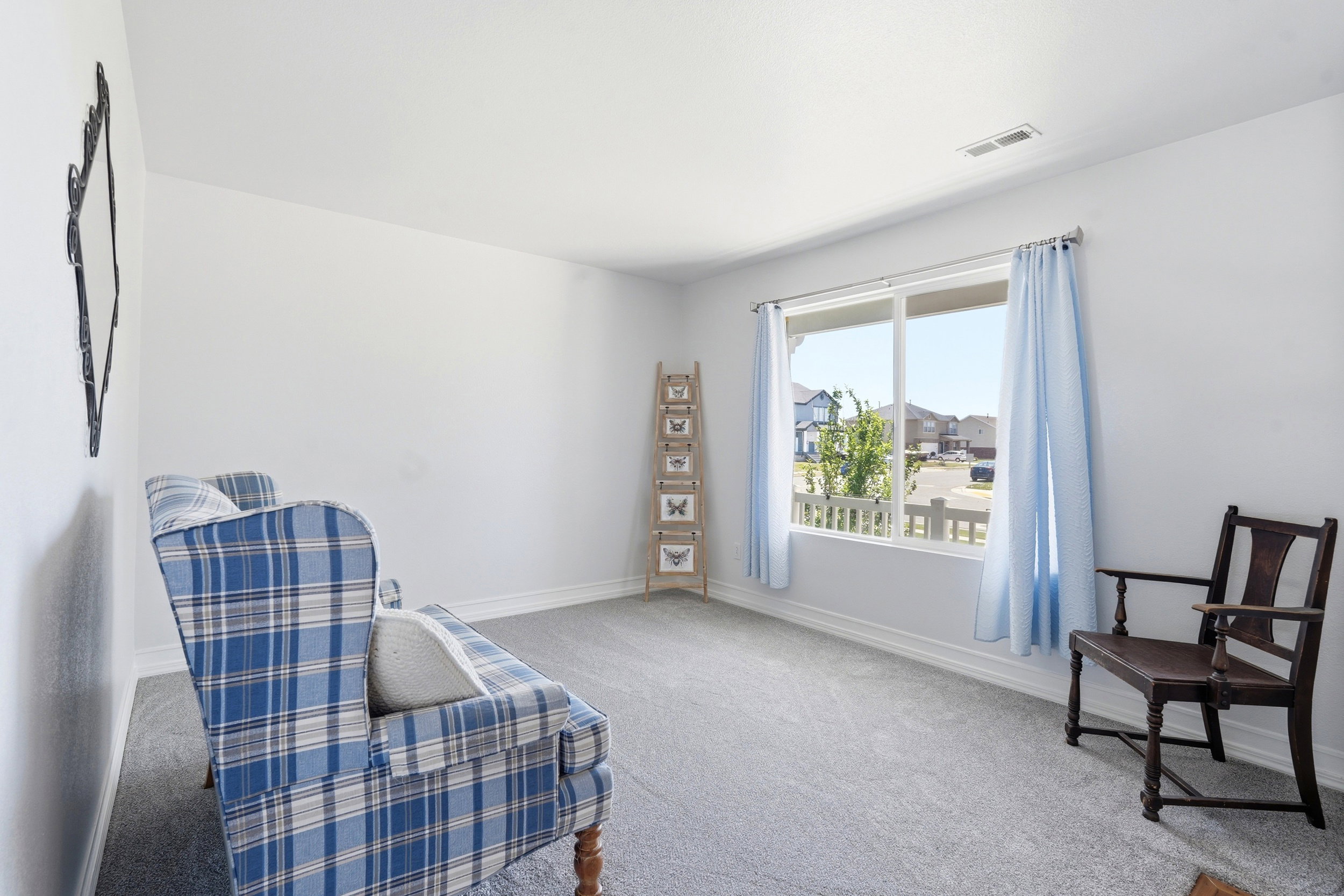 Carpeted room with a large window featuring white trim and blue curtains