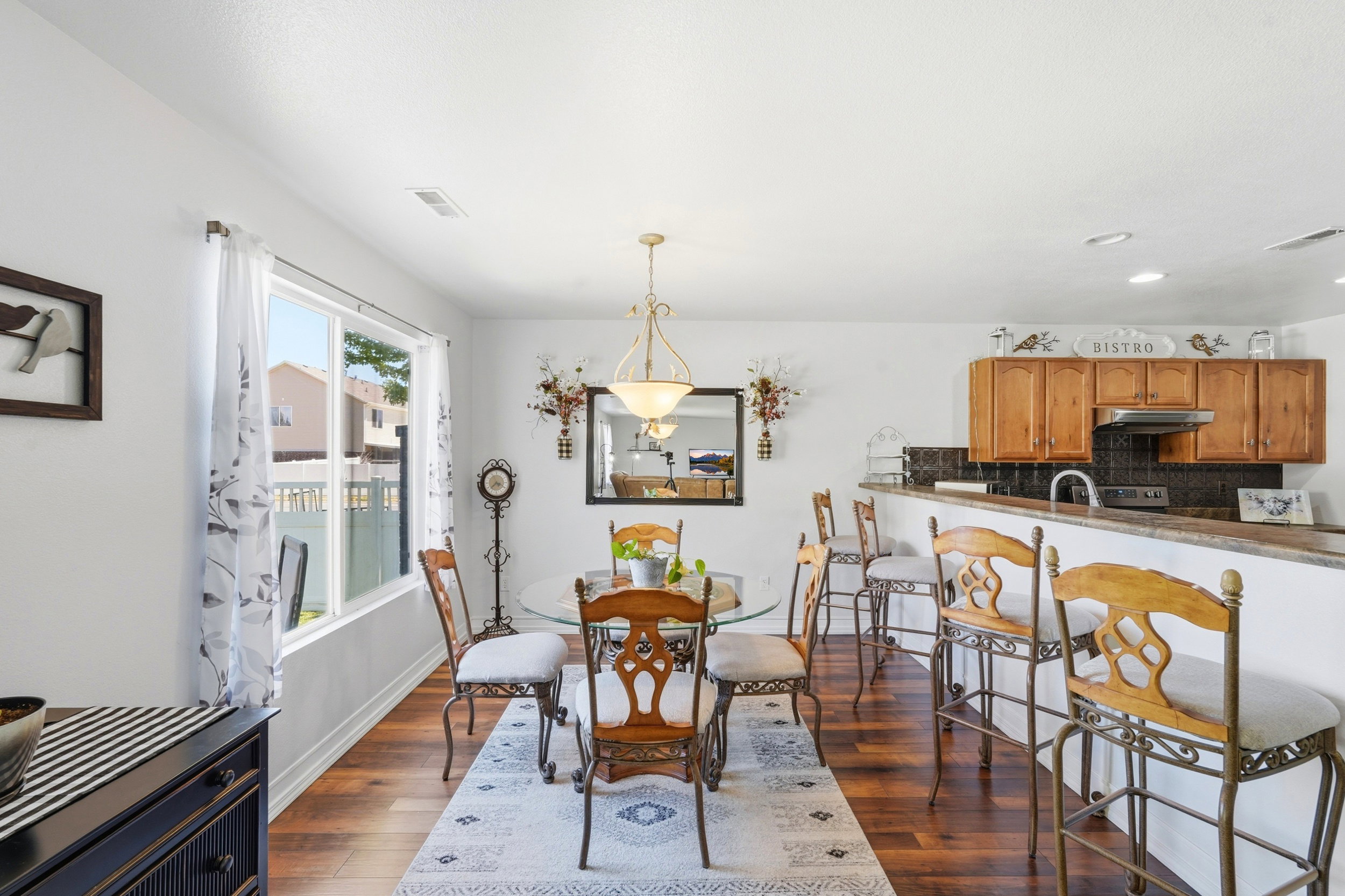 Open-concept dining area featuring wood-finish flooring, a contemporary chandelier, and a bright window