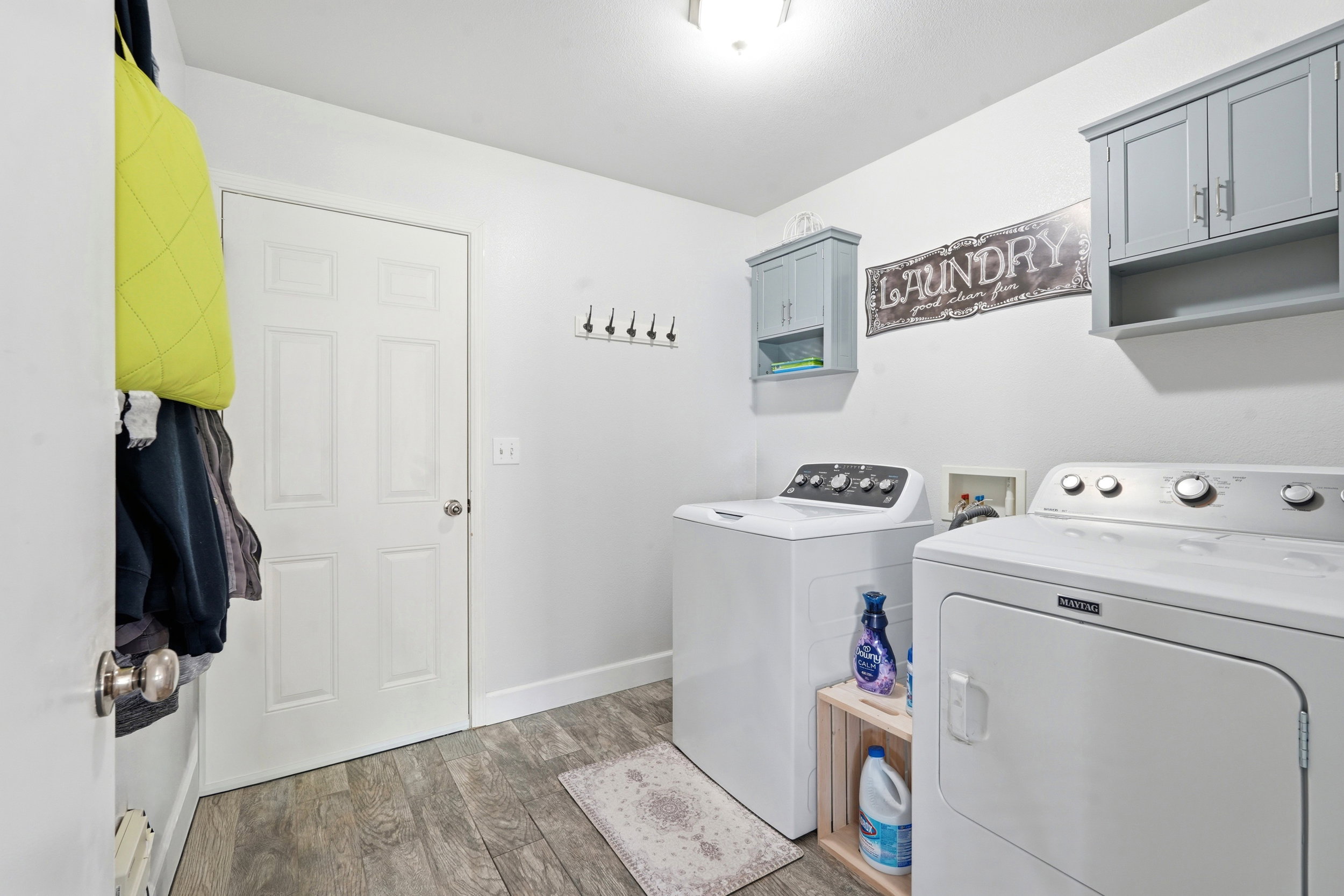 Dedicated laundry room featuring wood-finish flooring, white walls, and built-in gray cabinetry