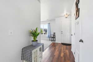 Foyer featuring wood-finish flooring, white paneled doors, and a decorative ceiling light fixture
