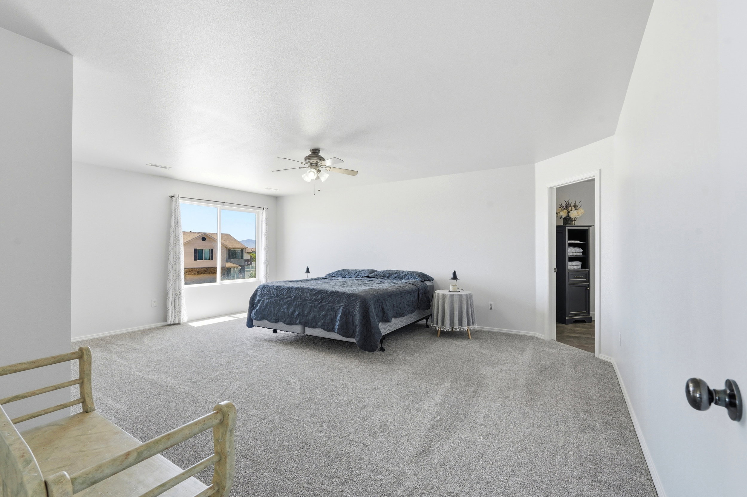 Spacious bedroom featuring light gray carpeting and a ceiling fan