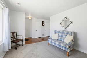 Bright interior space featuring light gray carpeting, white painted walls, a large window, a ceiling vent, and a flush-mount light fixture