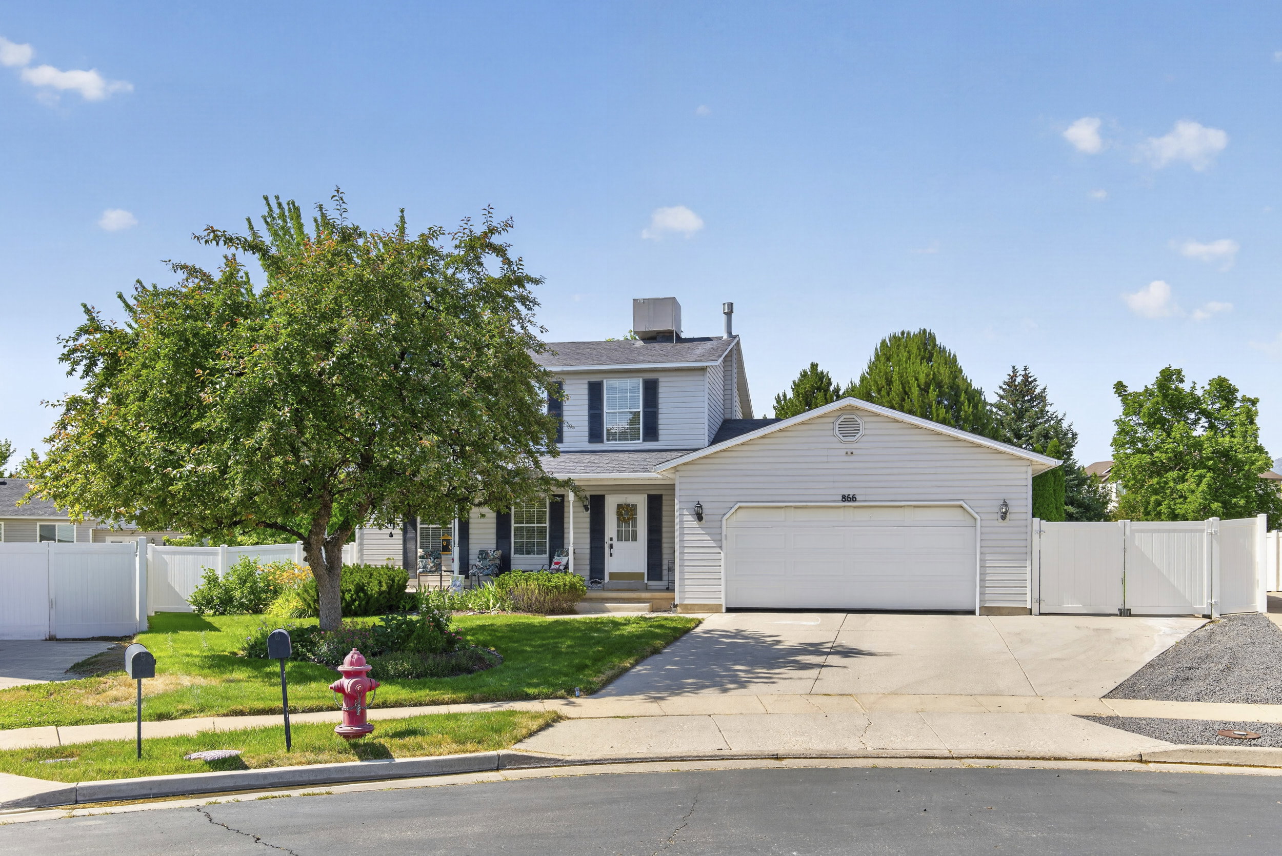 Two-story residence featuring light gray siding with contrasting dark shutters, an attached two-car garage, and a concrete driveway