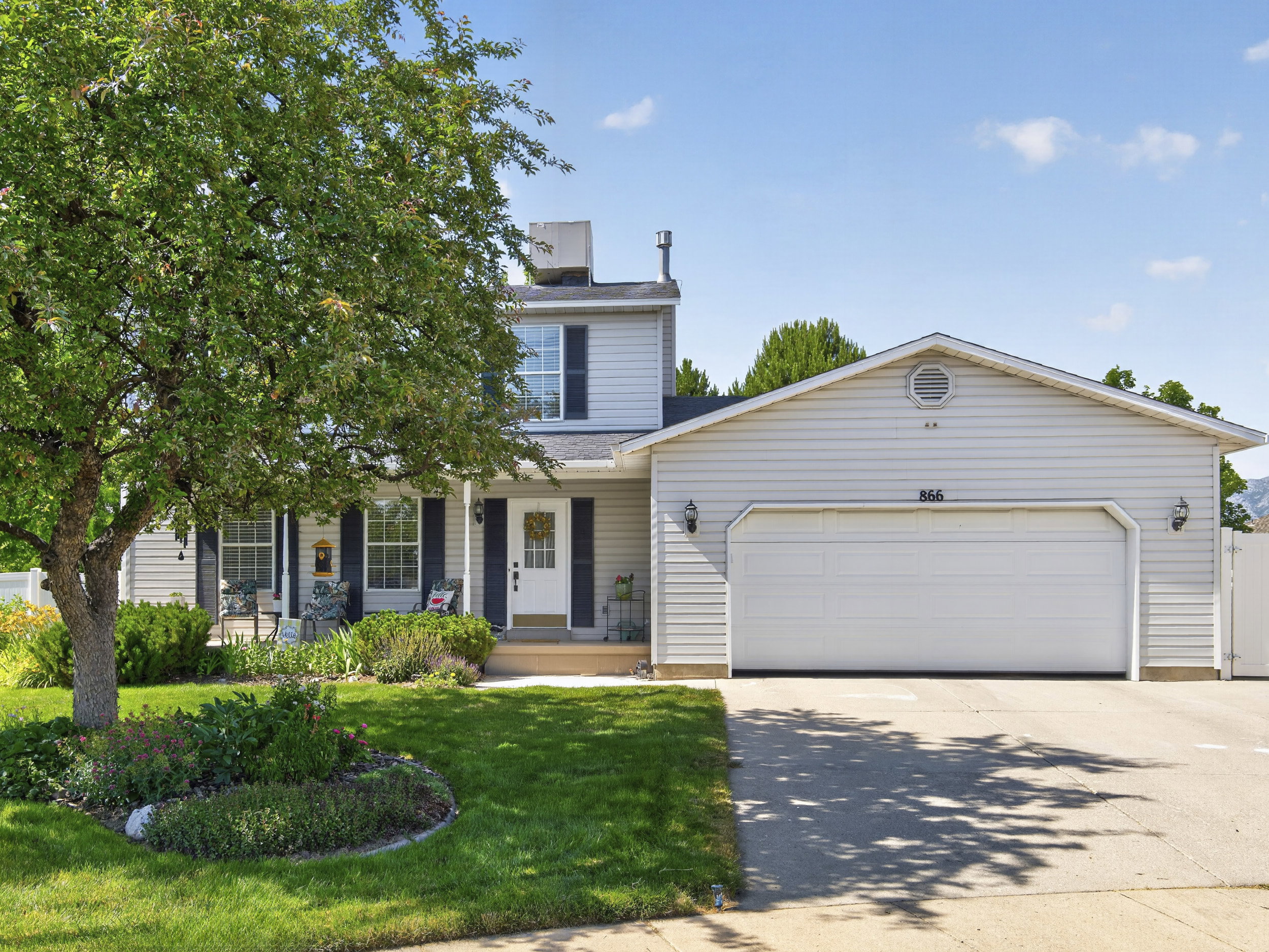 Traditional-style property featuring a two-car garage, light-colored siding, and a covered front porch