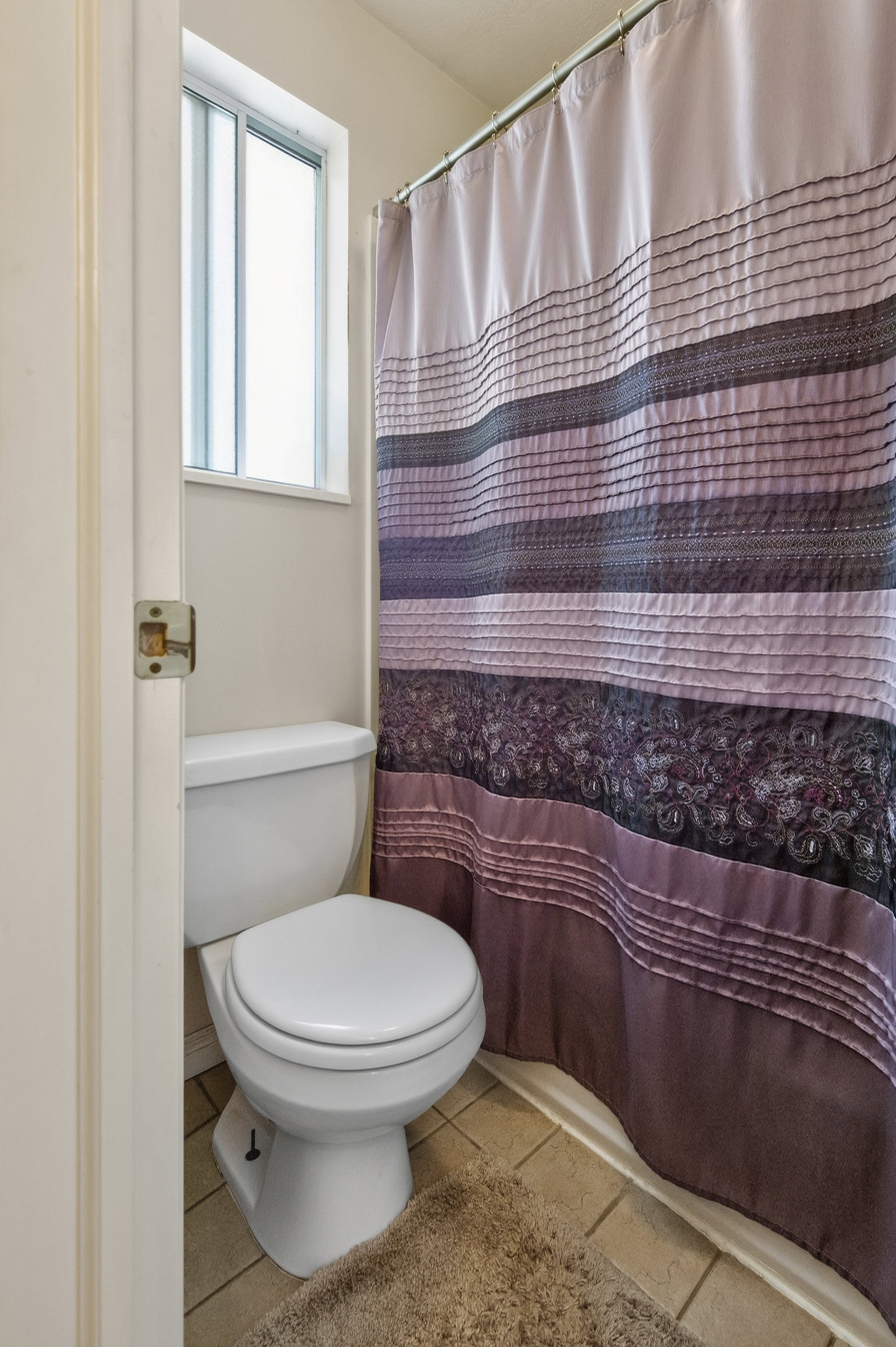 Bathroom featuring a white toilet, light-colored wall paint, and a window for natural light