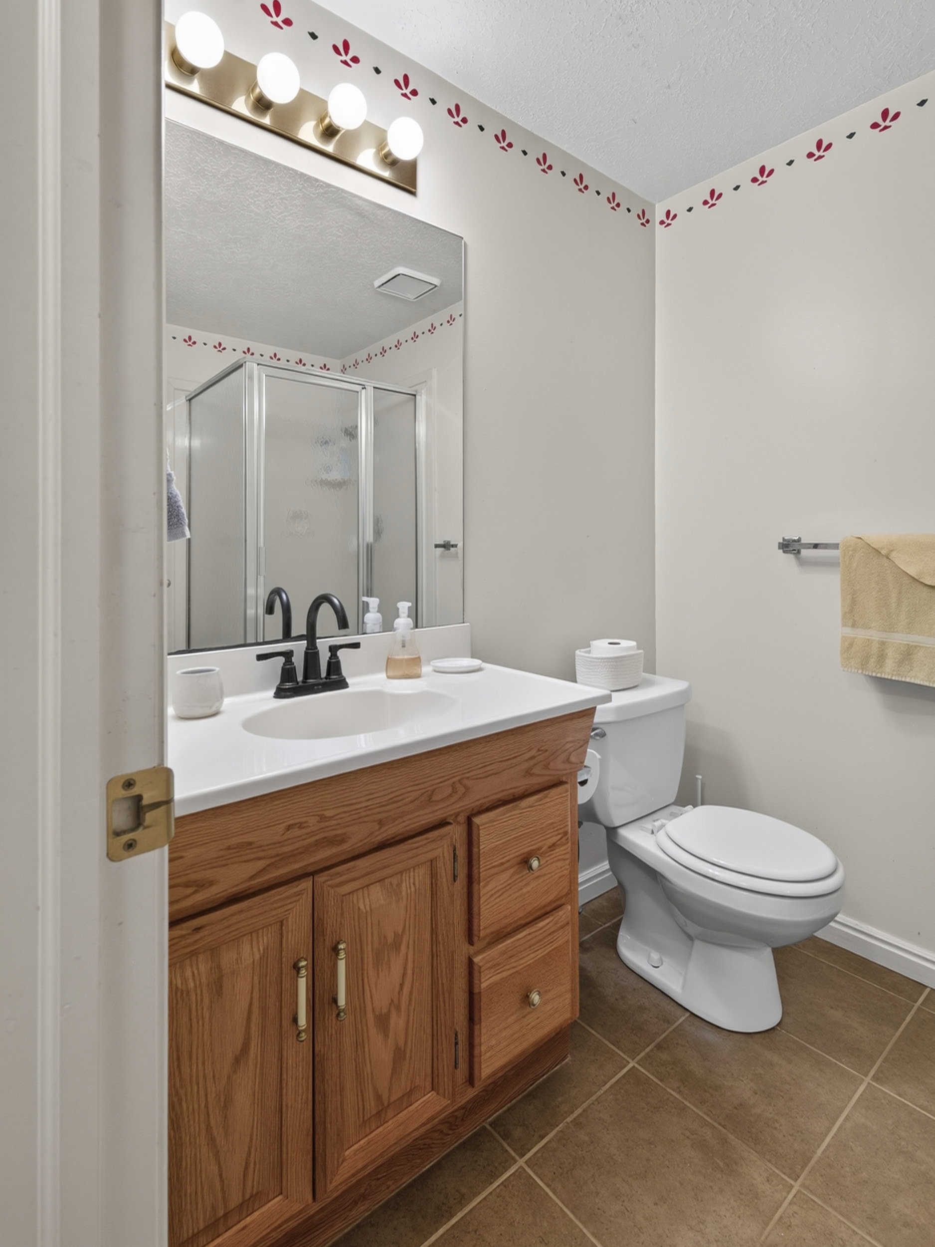 Full bathroom featuring a wood-finish vanity with a white countertop and integrated sink, a large wall-mounted mirror, and a shower with a sliding glass door