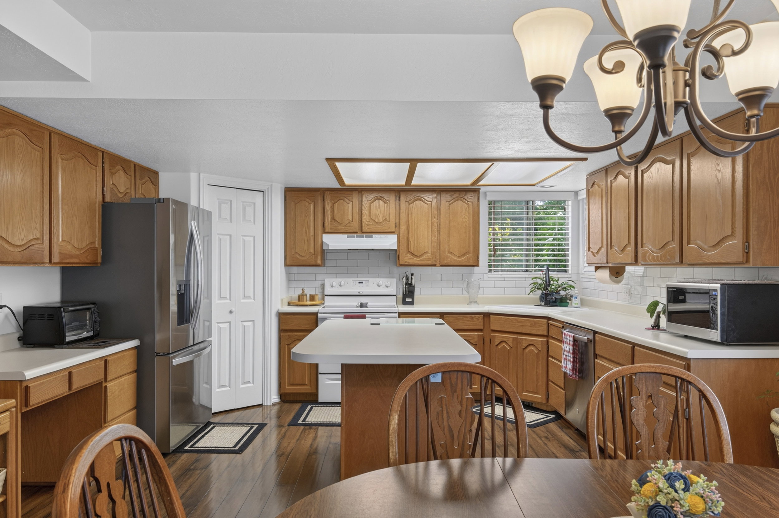 Kitchen featuring wood-finish cabinetry, white countertops, subway tile backsplash, and stainless steel refrigerator