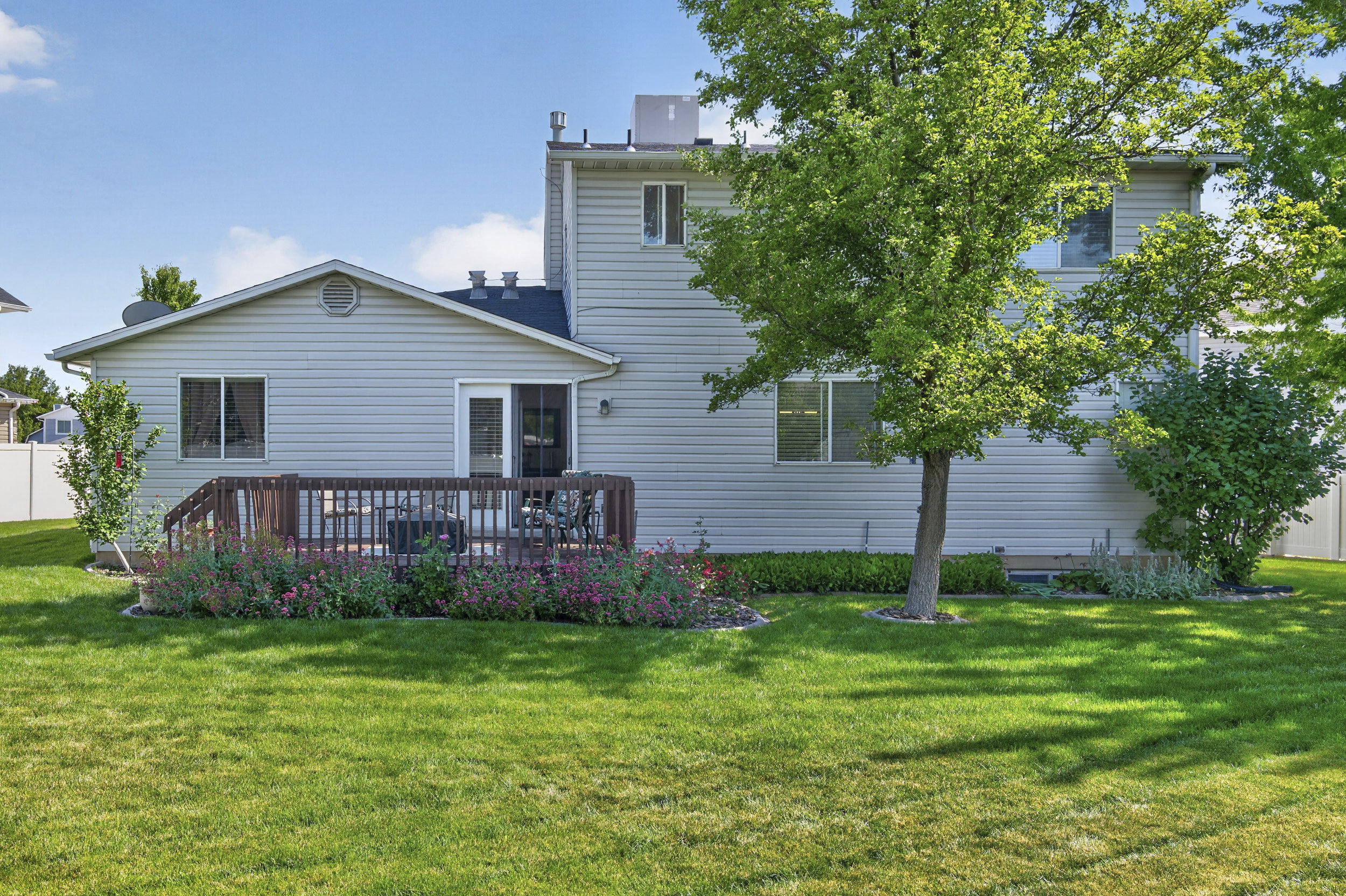 Backyard featuring a wooden deck with railing, sliding glass door access, and a manicured lawn