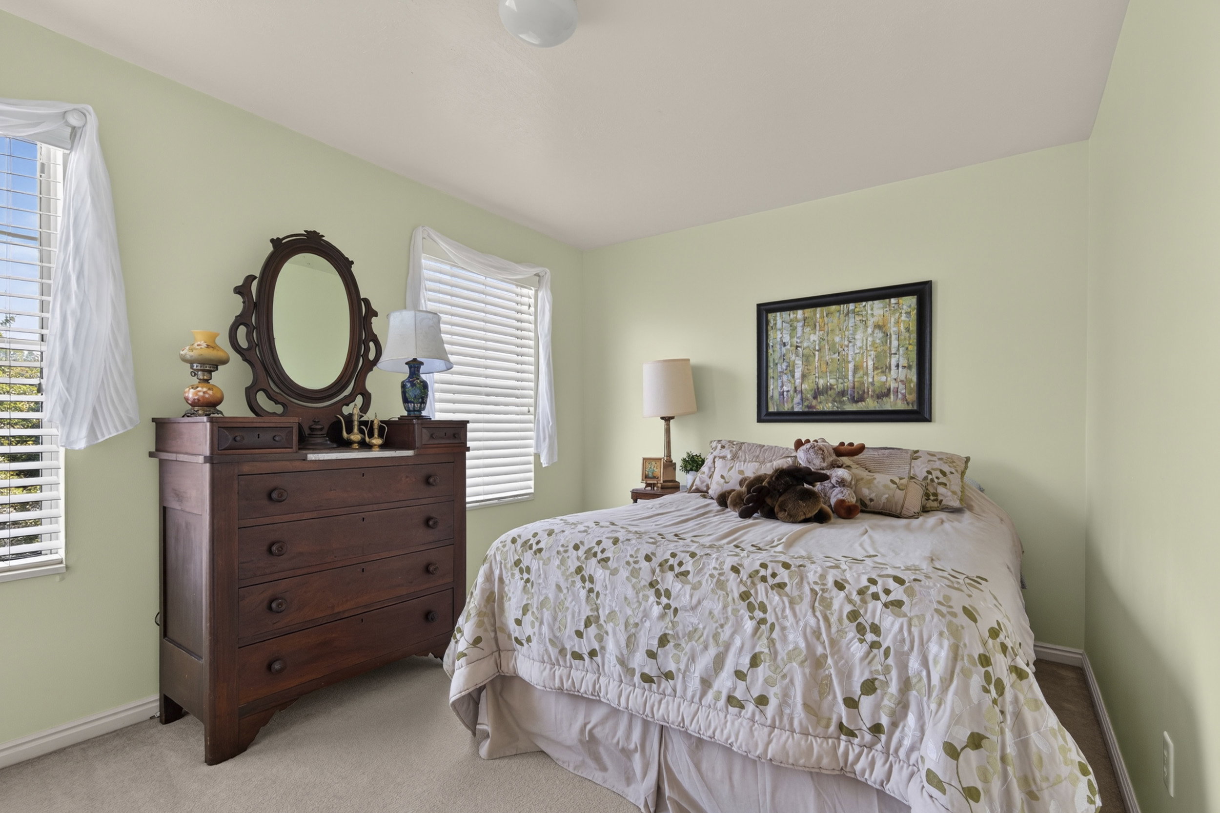 Bedroom featuring two windows with horizontal blinds, light-colored walls, and carpet flooring