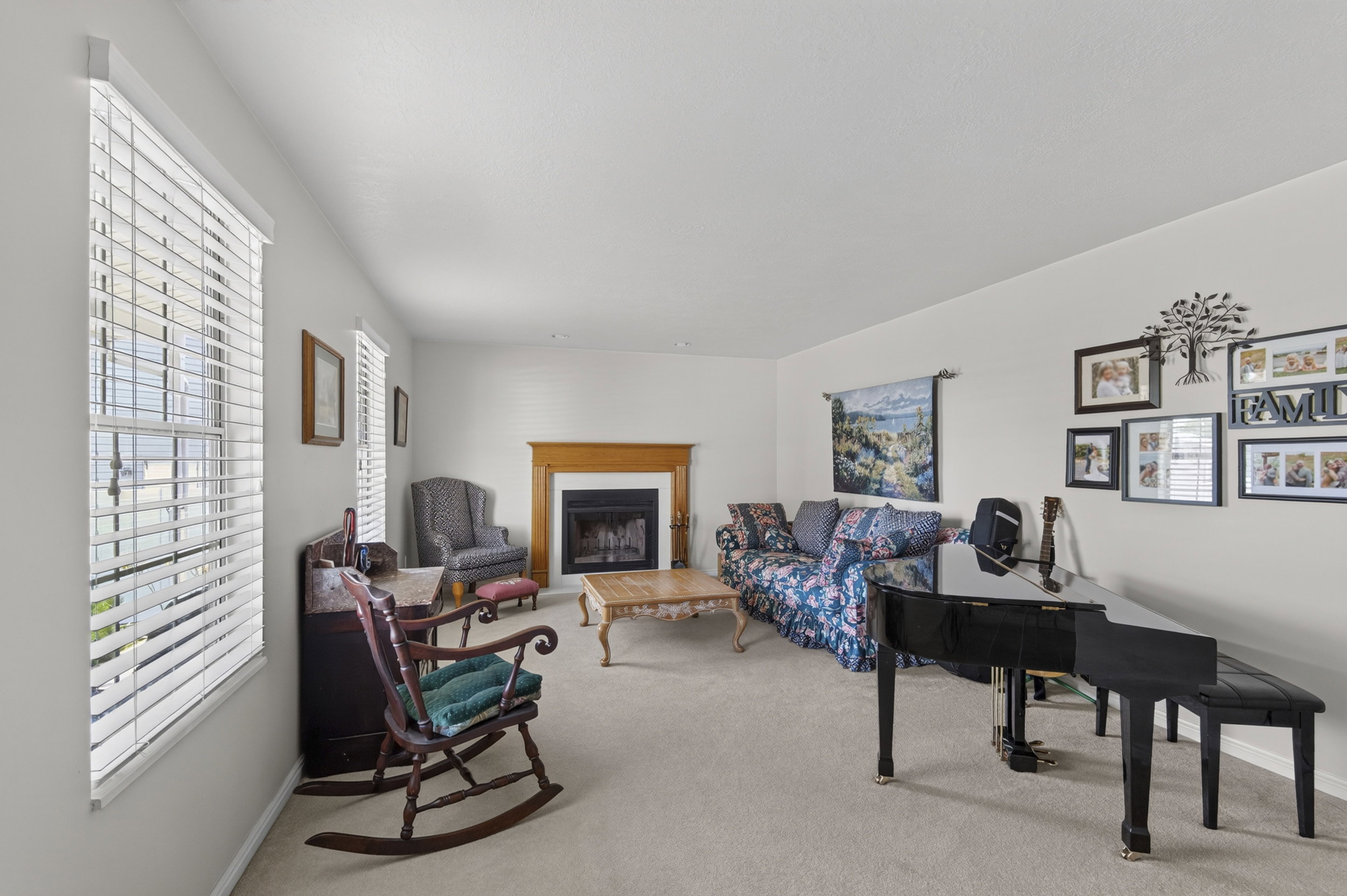 Carpeted living space featuring a fireplace with a wood-finish mantel and white surround