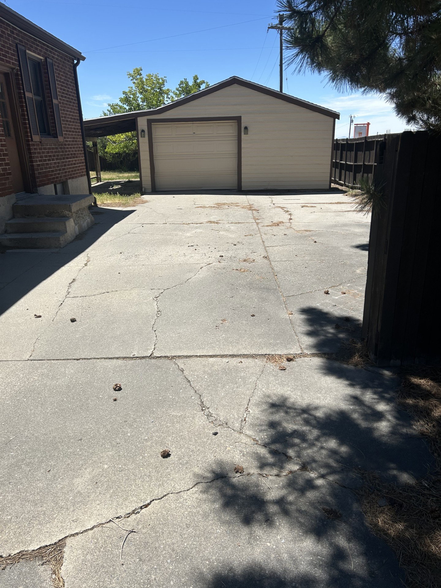 Detached garage with a single vehicle bay door, light-colored siding, and dark trim