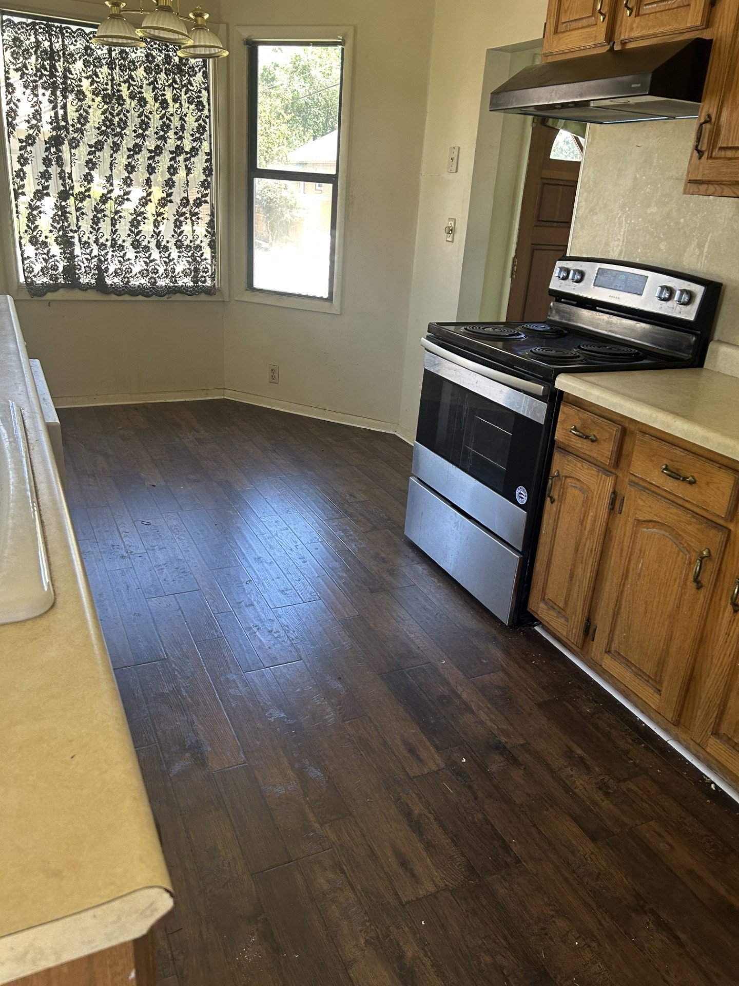 Kitchen featuring wood-finish flooring, stainless steel range, and wood cabinetry with light countertops