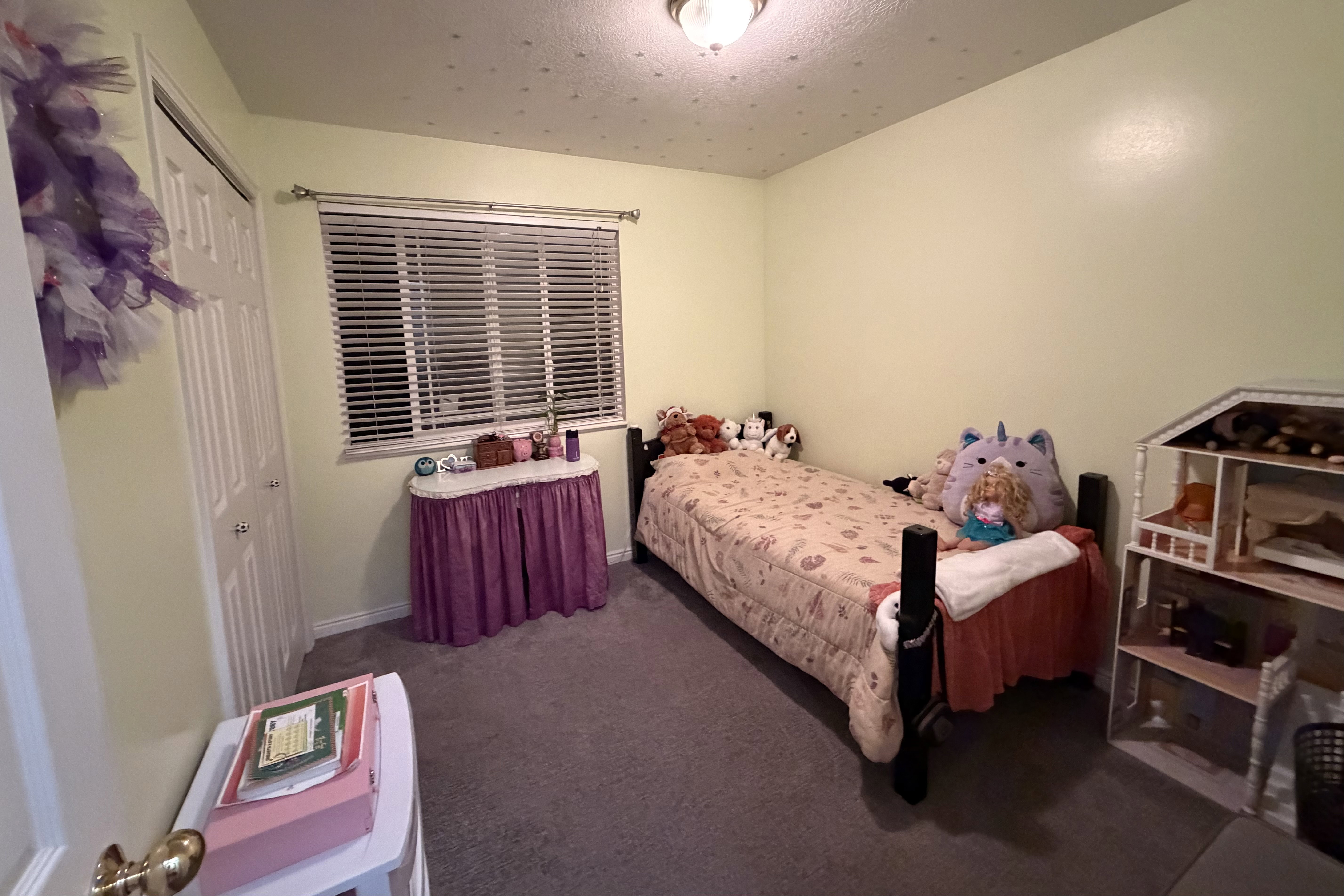 Carpeted room featuring a single window with horizontal blinds, a ceiling-mounted light fixture, and a built-in closet with bifold doors