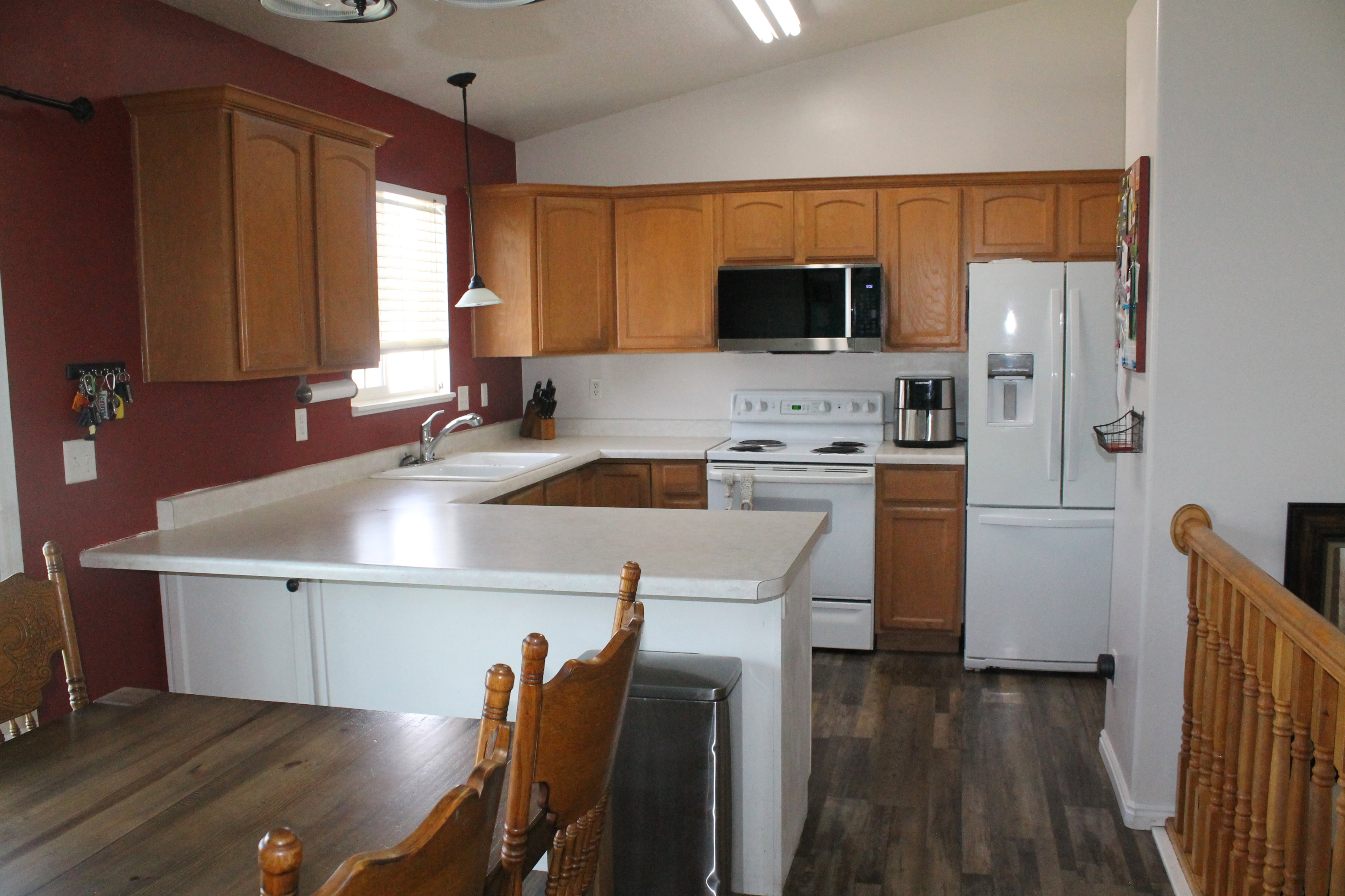 Kitchen featuring wood-finish flooring, light wood cabinetry, white countertops, and a white double basin sink with a window above