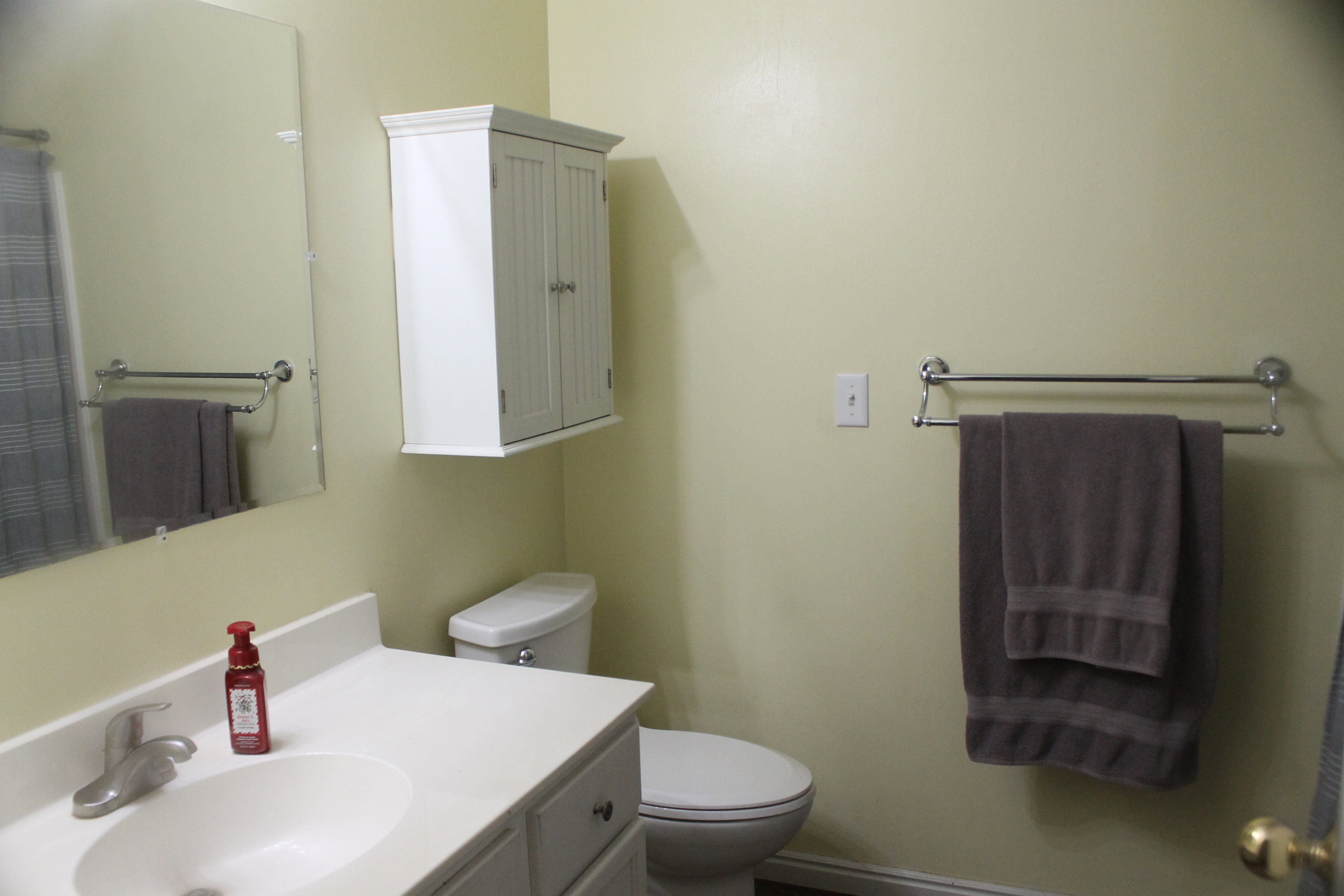 Bathroom featuring a white vanity with integrated sink, chrome faucet, and mirrored wall