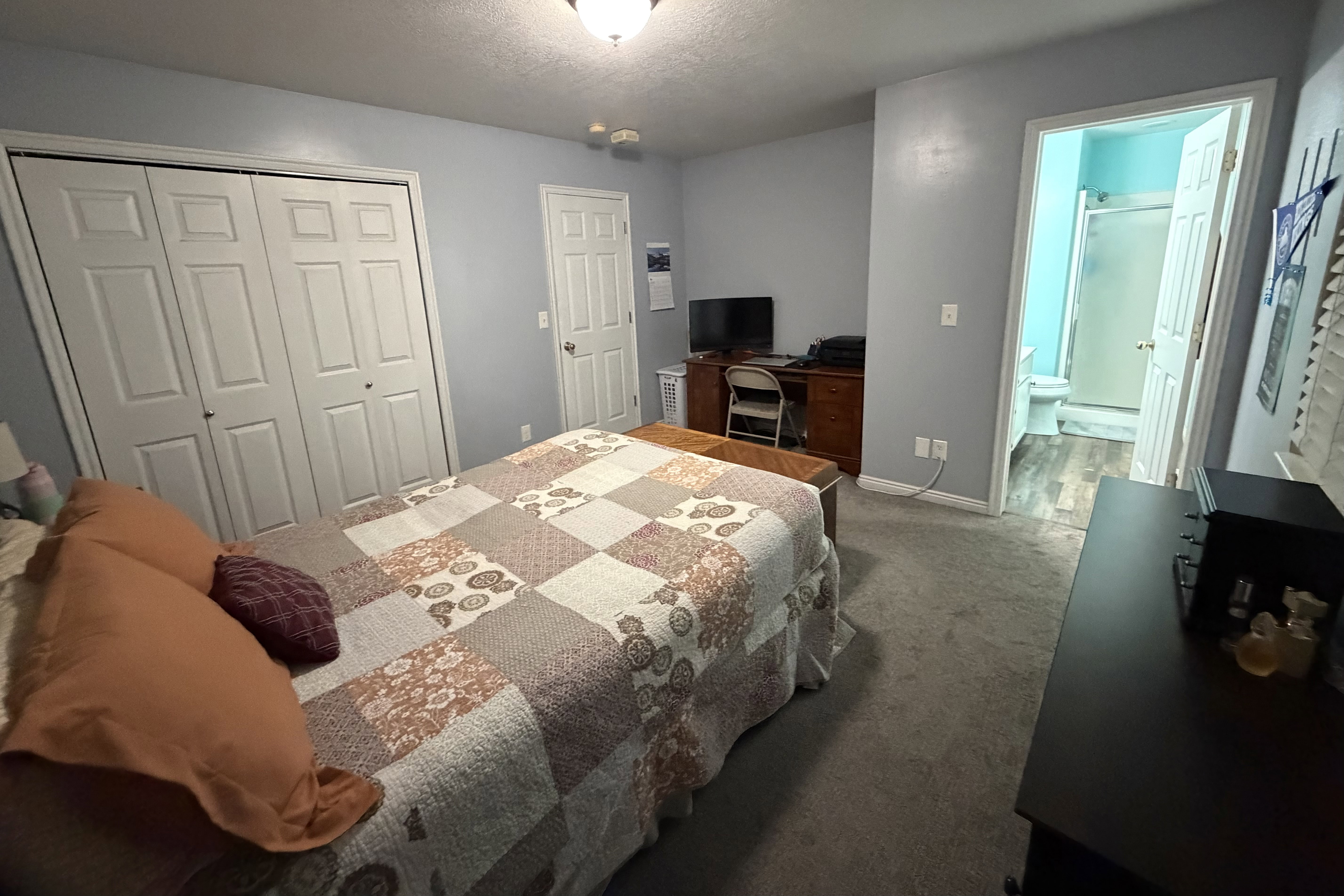 Carpeted bedroom with a double bi-fold closet, recessed lighting, and a private en-suite bathroom featuring wood-finish flooring and a glass-enclosed shower
