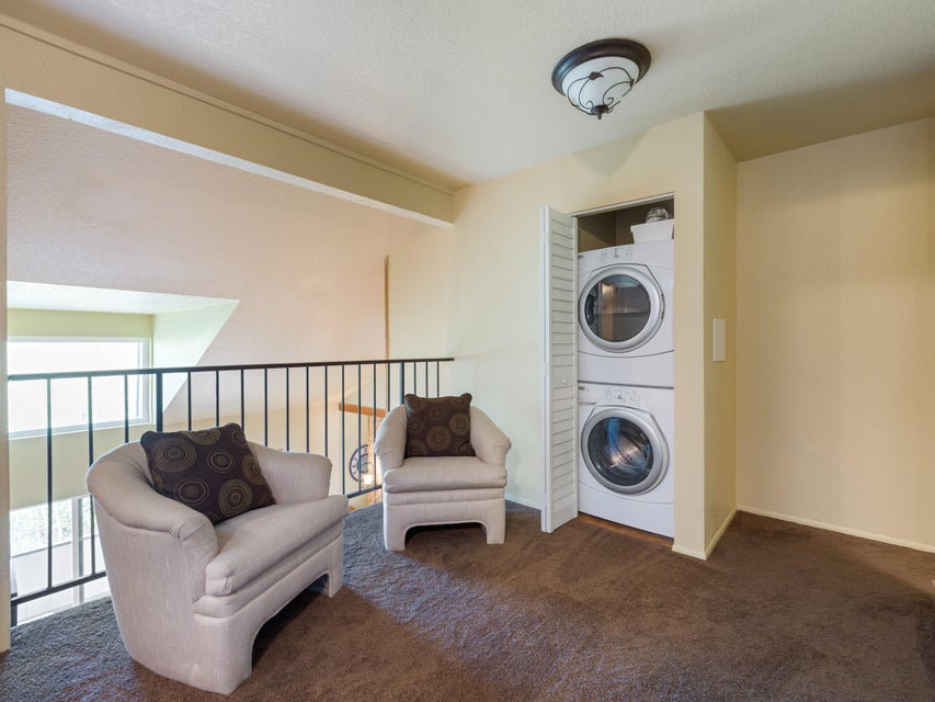 Carpeted upper-level landing with a stacked washer and dryer unit concealed by bi-fold doors