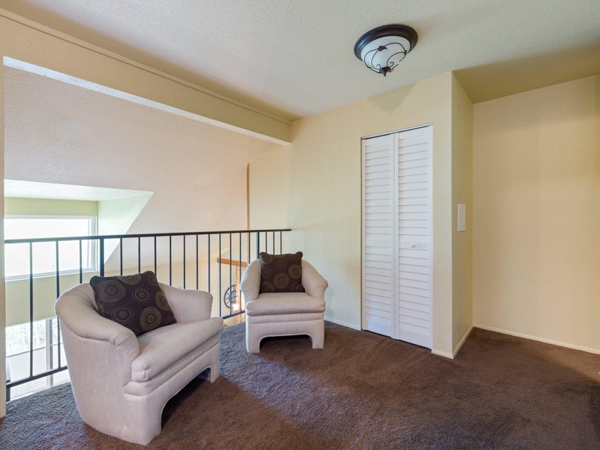 Carpeted loft area featuring a white louvered bifold door, a dark metal railing, and a semi-flush mount ceiling light fixture