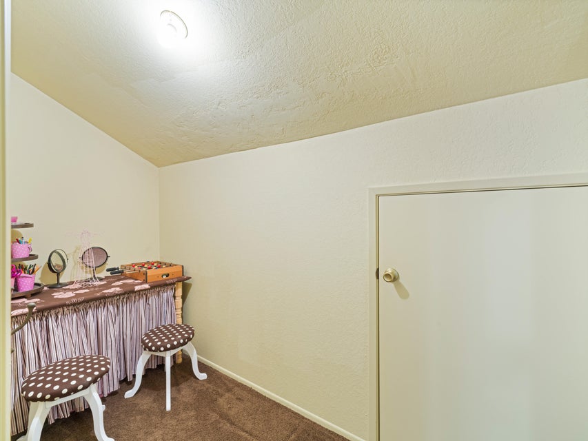 Carpeted room featuring a white door with a brass doorknob, light-colored walls, and a textured ceiling with a flush-mount light fixture