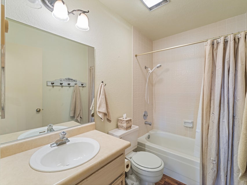 Full bathroom featuring a single-sink vanity with an oval basin, a combination shower and tub, and wood-finish flooring