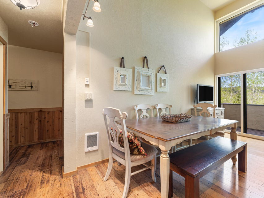 Dining area featuring wood-finish flooring, high ceilings with track lighting, a large window, and sliding glass doors opening to a balcony