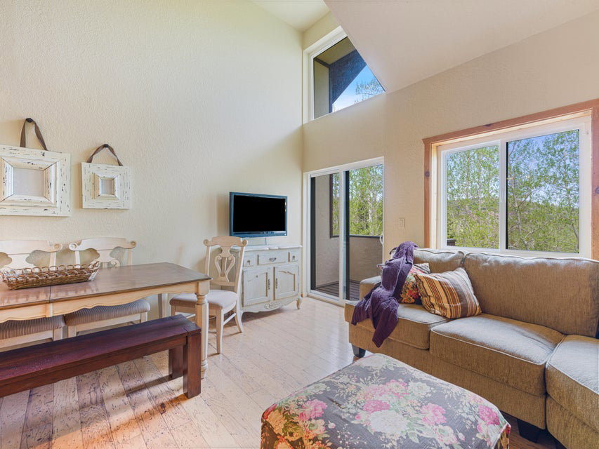 Living area featuring wood-finish flooring, a vaulted ceiling, and ample natural light from multiple windows