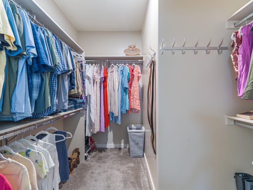 Walk-in closet featuring built-in shelving, multiple hanging rods, wall-mounted hooks, and carpeted flooring
