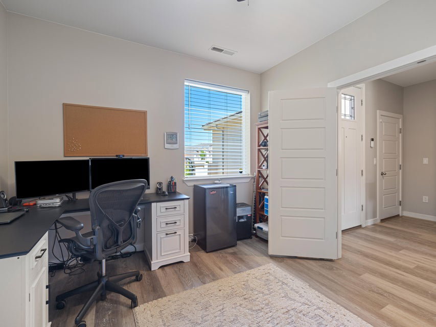 Light-filled room featuring wood-finish flooring, a window with horizontal blinds, and a five-panel interior door