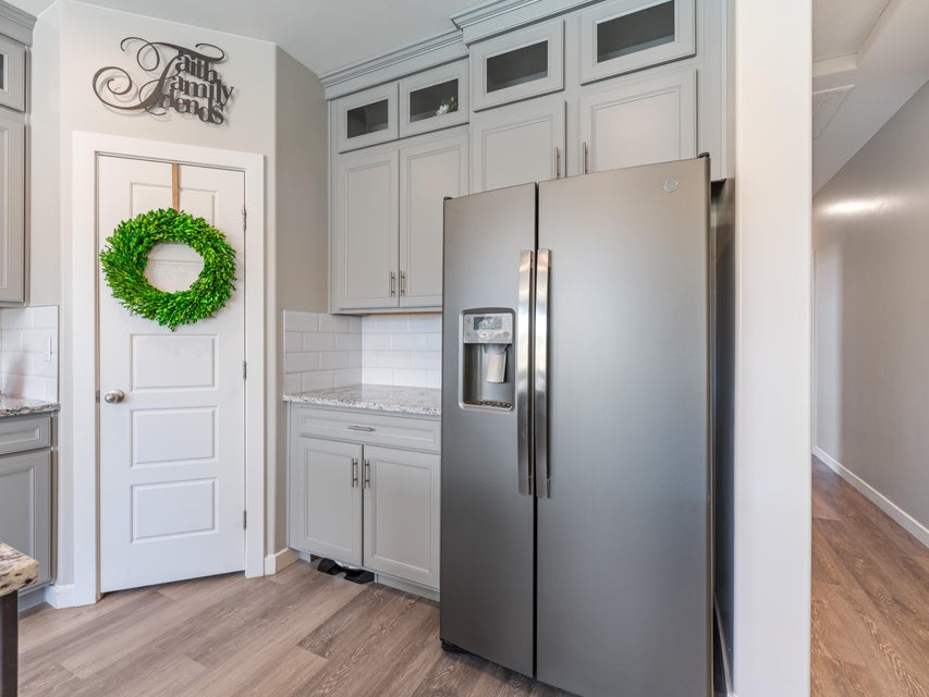 Kitchen area featuring light gray cabinetry, subway tile backsplash, granite-finish countertops, stainless steel side-by-side refrigerator, and wood-finish flooring