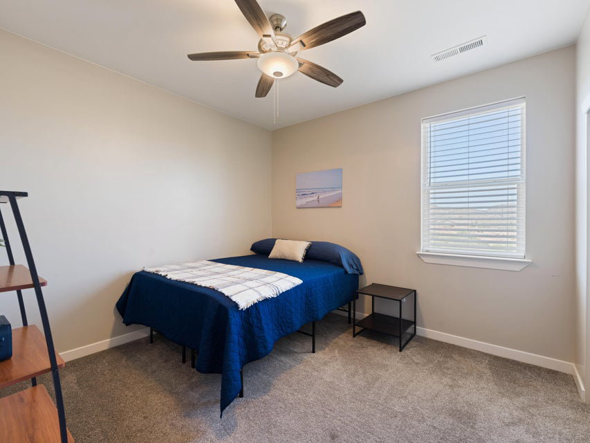 Carpeted room featuring a ceiling fan with light fixture, a window with horizontal blinds, and neutral wall tones