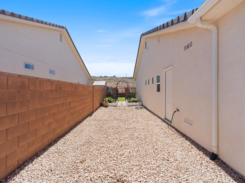 Gravel-covered side yard featuring stucco exterior, a block wall, and integrated drainage