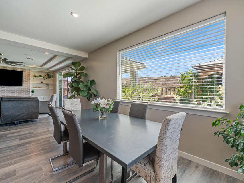Dining area featuring a wide window with horizontal blinds, wood-finish flooring, and recessed lighting