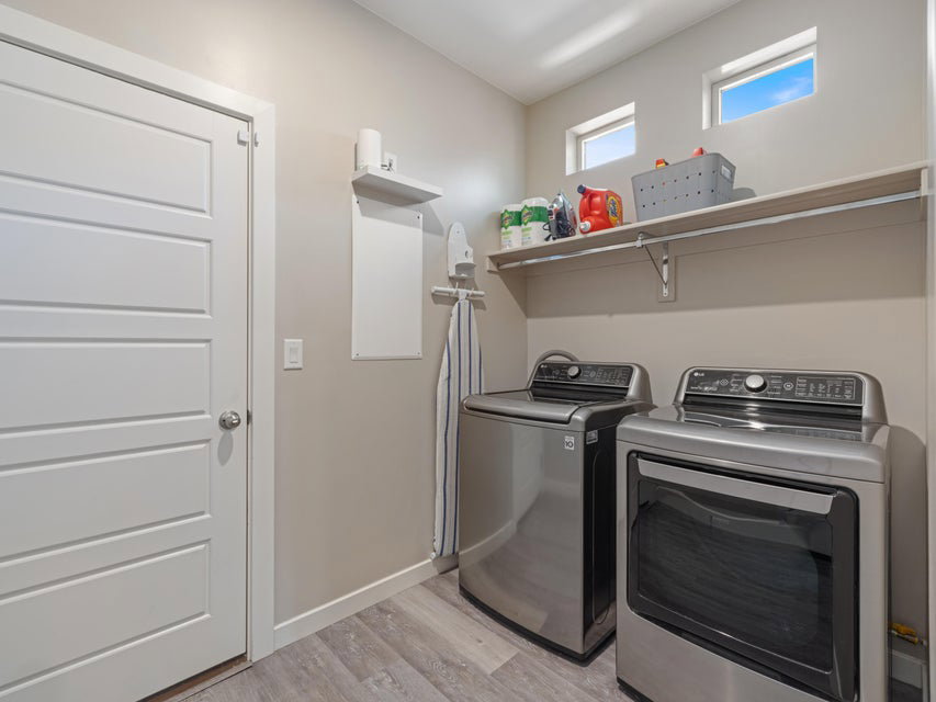 Dedicated laundry room featuring light gray walls and wood-finish flooring
