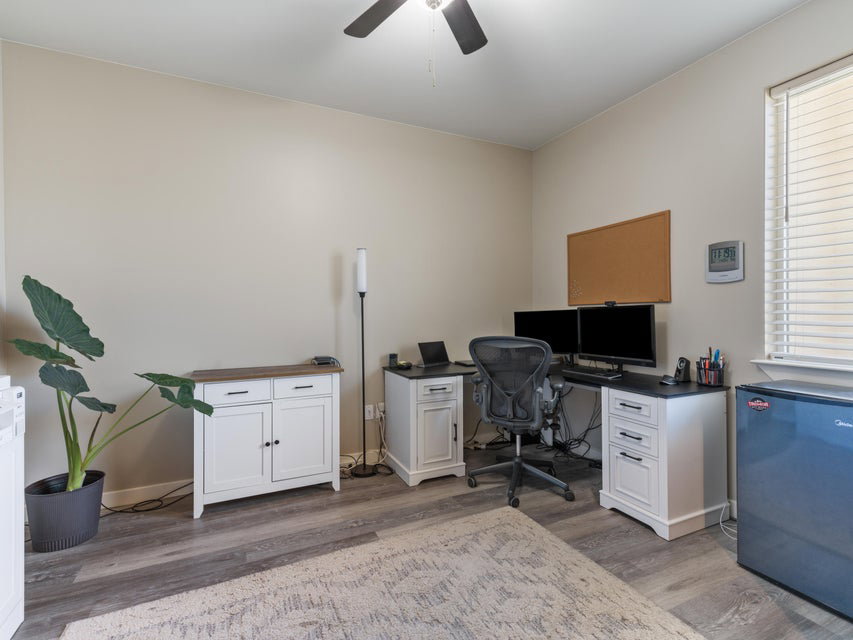 Room featuring wood-finish flooring, a ceiling fan with light fixture, and neutral painted walls