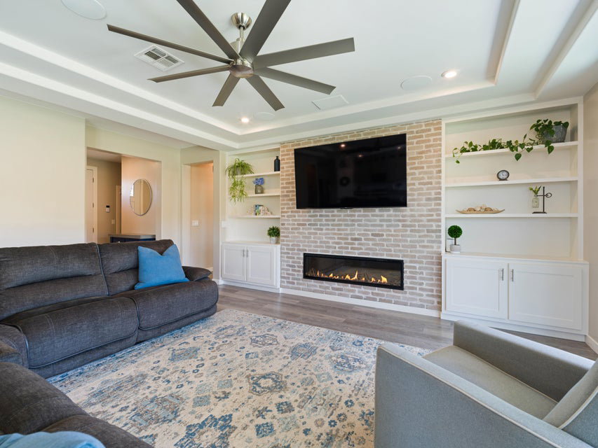Living area featuring a textured brick accent wall with an elongated linear fireplace
