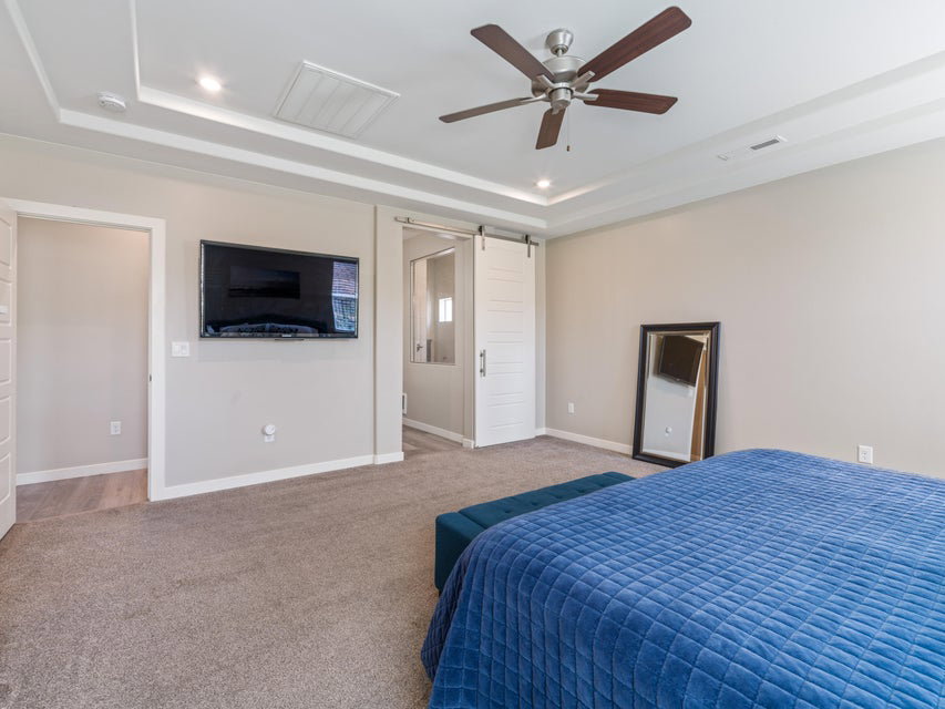 Bedroom featuring tray ceiling with recessed lighting, ceiling fan, and carpeted flooring