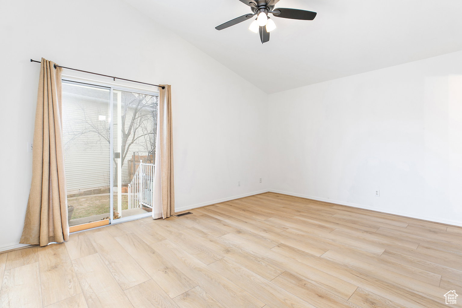 Spacious room featuring vaulted ceilings and light wood-finish flooring